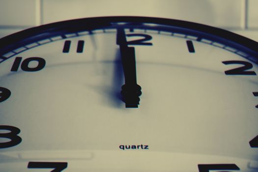 Detailed close-up shot of a wall clock showing the hour hand at midnight, highlighting time concept.