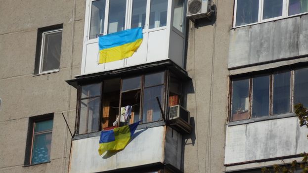 Apartment building facade in Odesa, Ukraine, displaying Ukrainian flags waving in the breeze.