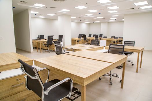 Spacious modern office with wooden desks and ergonomic chairs, ideal for productivity.