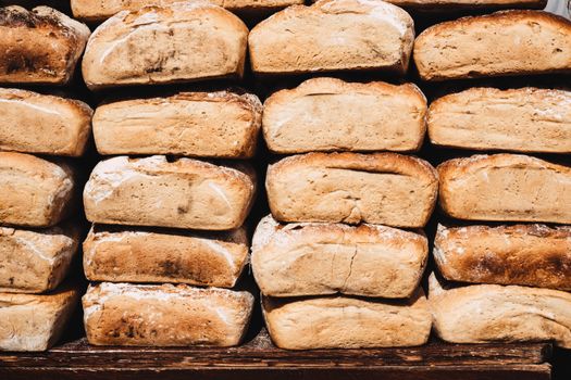 A stack of freshly baked rustic bread loaves on a wooden board. Perfect for bakery promotions.
