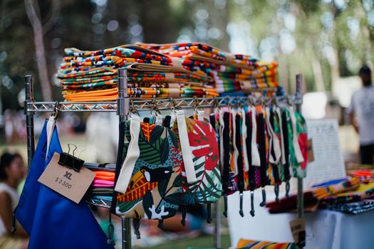 Vibrant handmade bags and textiles displayed at an outdoor market.