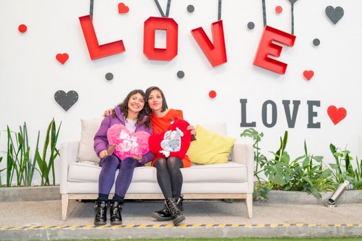 Two women sitting on a sofa with love decorations in Ciudad de México.