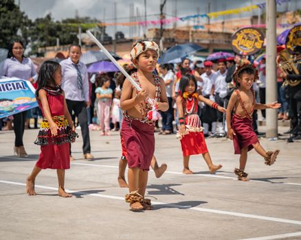 Children in traditional indigenous outfits participating in a lively street parade in San Martín, Peru.