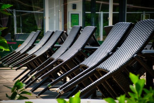 A row of stylish wicker lounge chairs lined up on an outdoor terrace, offering a relaxing summer ambiance.