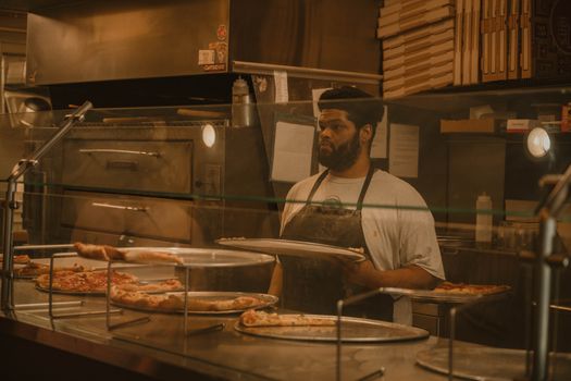 Pizza chef serving slices in a Milwaukee pizzeria, captured in warm tones.