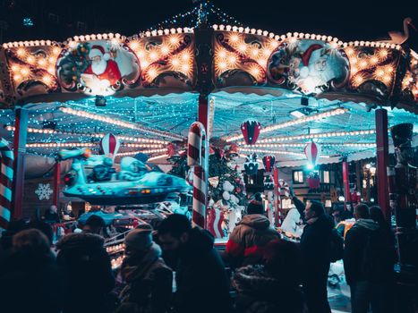 Vibrant Christmas market carousel at night with festive lights and decorations.