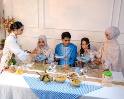 A joyful family enjoying a traditional iftar meal in Jakarta, dressed in cultural attire.