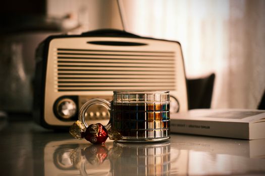 Cozy indoor scene with a retro radio, coffee, and chocolates on a table.