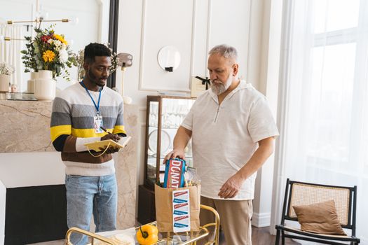 Two male volunteers packing donation bags with essentials indoors.