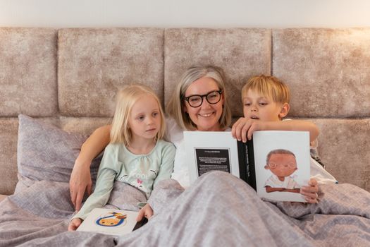 A grandmother reads bedtime stories to her two grandchildren, creating a warm family bond.